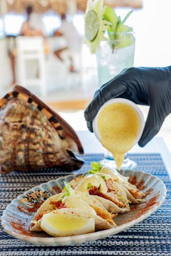 a person in black gloves holding a drink and a plate of food at Playa Palmera Beach Resort in Punta Cana