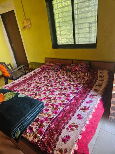 a bedroom with a bed with a floral blanket on it at Advait Holiday Home in Nagaon