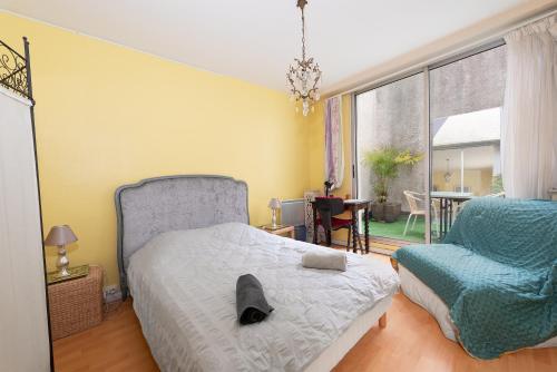 a bedroom with a bed and a chair and a window at T2 Centre Saint Girons in Saint-Girons