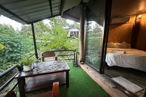 a room with a bed and a table on a balcony at Baansuan Chomchun in Amphoe Mae Taeng