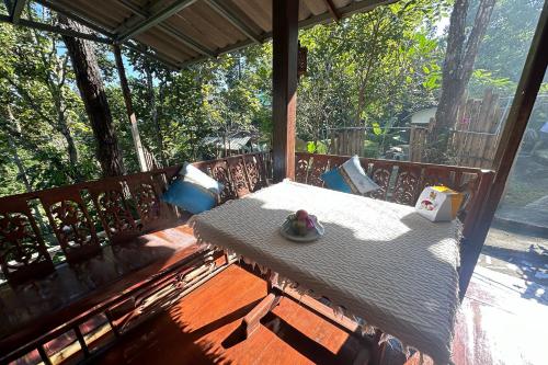 a wooden bench with a table on a porch at Baansuan Chomchun in Amphoe Mae Taeng