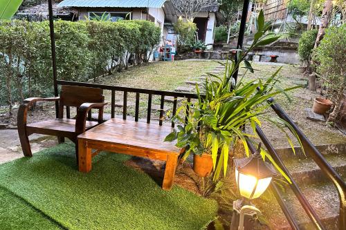 a wooden bench sitting in a yard with a plant at Baansuan Chomchun in Amphoe Mae Taeng