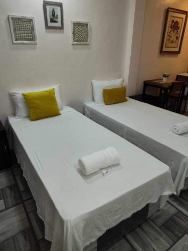 two beds in a room with yellow pillows at Point Gate Inn in Bacolod