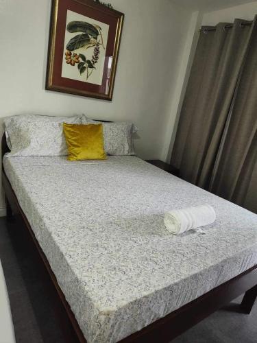 a bed in a bedroom with a yellow pillow on it at Point Gate Inn in Bacolod