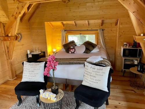 - une chambre avec un lit avec un ours en peluche et 2 chaises dans l'établissement Cabane insolite 2 p Jacuzzi Domaine du Marais 91 Magnolia, à Maisse
