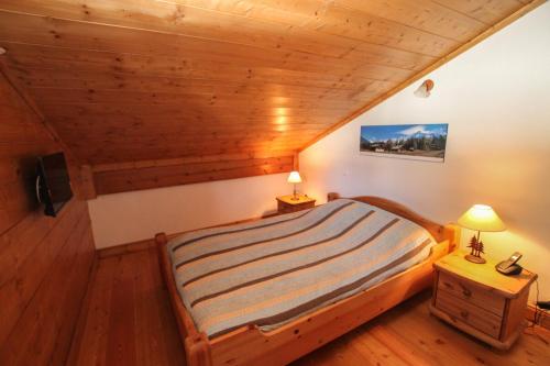 une chambre avec un lit et un plafond en bois dans l'établissement Au pied des pistes, dans une résidence de standing, à Cohennoz