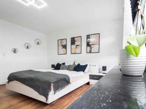 a white bedroom with a white bed with a gray blanket at Ferienwohnung Sunny in Schmallenberg