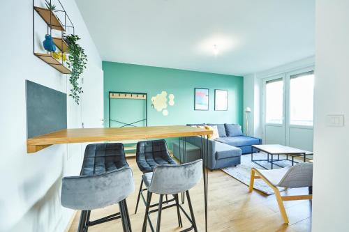 un salon aux murs bleus et un bar avec tabourets dans l'établissement BE-2D - Appartement F3 pour 1-4 pers 2ème étage au centre de Mulhouse, à Mulhouse