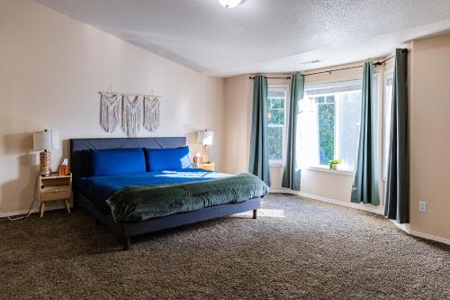 a bedroom with a blue bed and a window at Backyard hot tub for your family in Vancouver