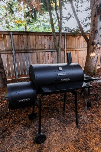 a black barbecue grill sitting in front of a fence at Backyard hot tub for your family in Vancouver