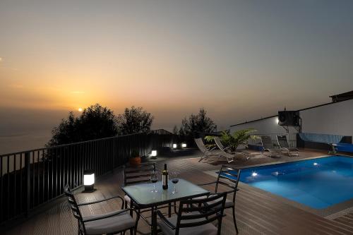 a patio with a table and chairs next to a swimming pool at Villa Panorâmica III in Arco da Calheta