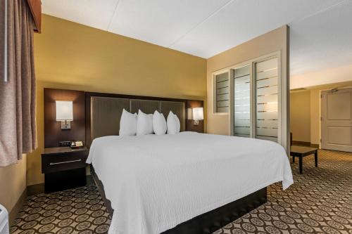 a hotel room with a large bed with white sheets at Best Western Plus InnTowner Madison in Madison