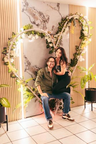 a man and a woman sitting in front of a heart wall at Fernandina Hotel & Spa in Puerto Ayora