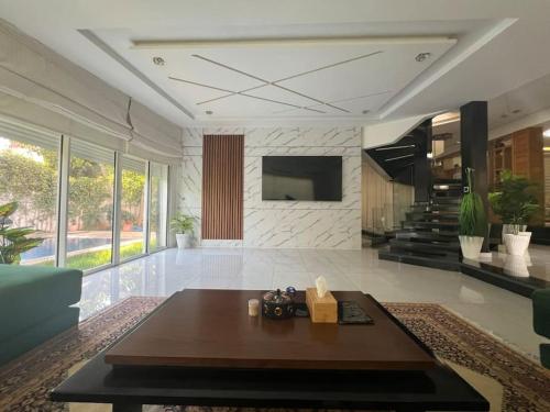 a living room with a table and a tv at Villa Lalla Laroussa in Kenitra