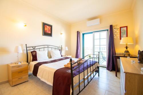 Casa Tara - Lovely Carvoeiro apartment في برايا دو كارفويرو: غرفة نوم بها سرير ونافذة كبيرة