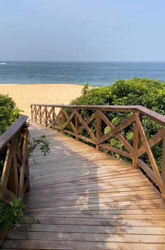a wooden boardwalk leading to a beach with the ocean at Incrível Chalé no Estaleiro à Beira Mar em Condomínio in Camboriú