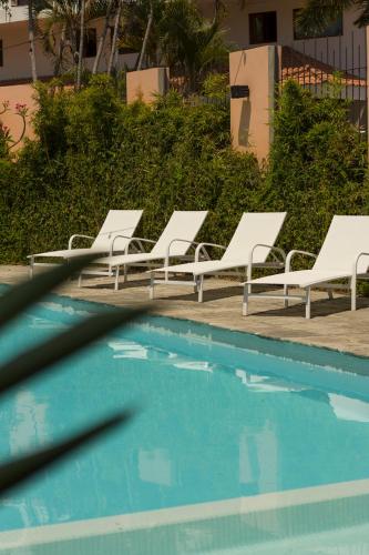 a group of white lounge chairs next to a swimming pool at San Trópico Boutique Hotel & Peaceful Escape in Puerto Vallarta