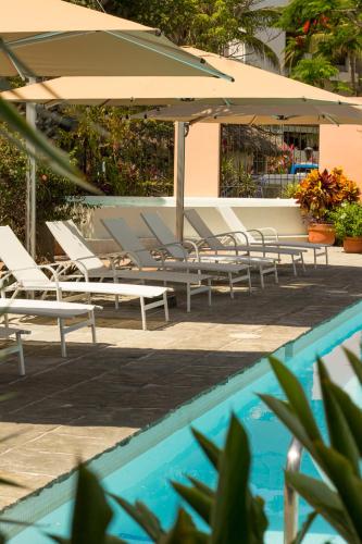 a group of lounge chairs and an umbrella next to a pool at San Trópico Boutique Hotel & Peaceful Escape in Puerto Vallarta