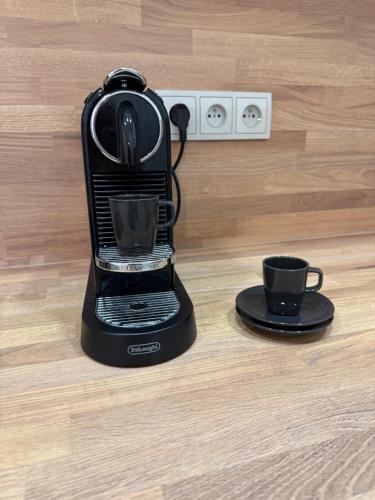a black coffee maker with a cup on a wooden floor at Apartmány U Kostela in Uničov