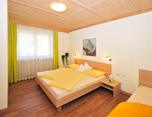 1 dormitorio con 1 cama grande con sábanas amarillas en Residence Mignon, en Rifiano