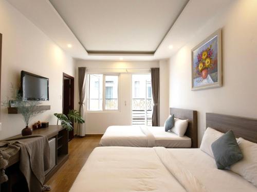 a hotel room with two beds and a tv at K HO DISCOVERY Guest House in Da Lat