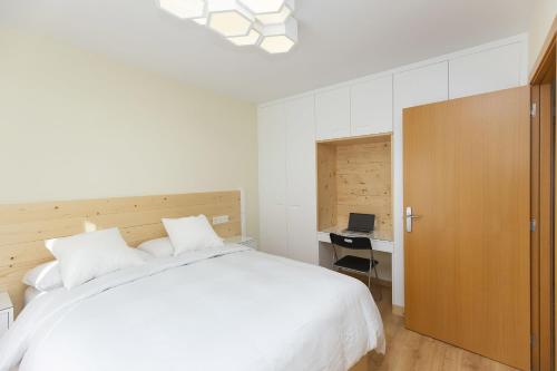 Un dormitorio con una cama blanca grande y un escritorio en Casa Lite by BeValle, en Escarrilla