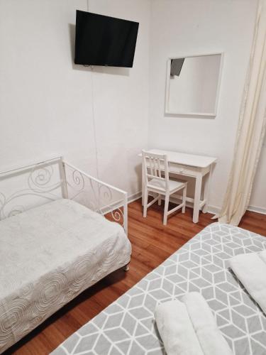 a bedroom with two beds and a desk with a television at Hospedaria Pôr do Sol in Funchal
