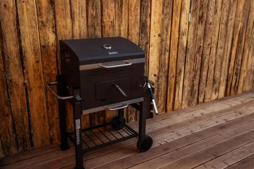 a grill on a stand in front of a wooden fence at Dom nad jeziorem Mazury - Pod Napięciem 2 in Mrągowo