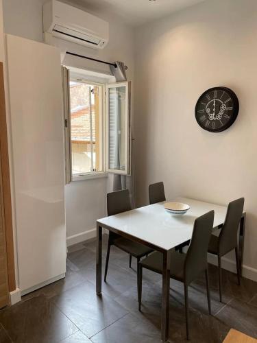 une salle à manger avec une table, des chaises et une horloge dans l'établissement Massena : Hyper Centre Studio 2p, à Nice