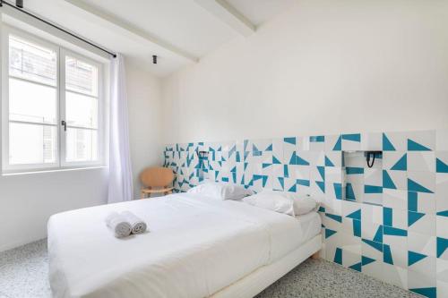 a bedroom with a white bed with a geometric wall at 3CAPU3 - Cosy T2 refait à neuf - Noaille in Marseille