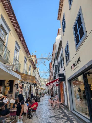 a group of people sitting at tables in a street at Art House Funchalet in Funchal