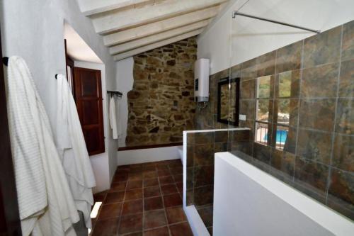 a bathroom with a tub and a stone wall at Lagar De Trevenez Montes De Malaga in Málaga