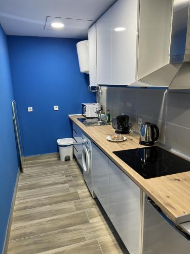 une cuisine avec des armoires blanches et un mur bleu dans l'établissement A&R Apartamento Santiago II, à San Sebastián de los Reyes