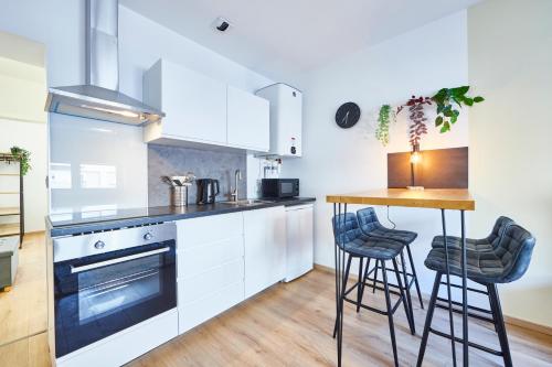 une cuisine avec des armoires blanches et une table avec des tabourets dans l'établissement BE-3G - Appartement F2 pour 1-2 pers au 3ème étage au centre de Mulhouse, à Mulhouse