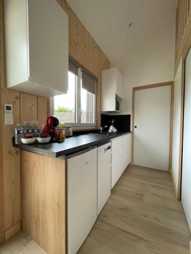 une cuisine avec des armoires blanches et un comptoir dans l'établissement Le petit chalet de la Ronzière de Miss K, à Cormoranche-sur-Saône