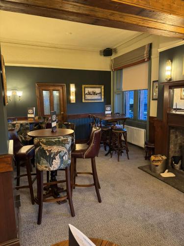 a dining room with tables and chairs and a fireplace at Agricultural Inn in Penrith