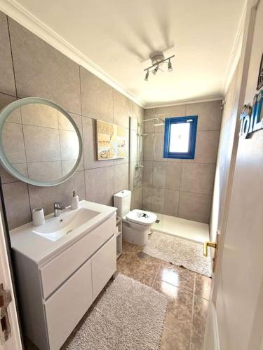 a bathroom with a sink and a toilet and a mirror at Casa del Sur good vibes only in Costa Calma