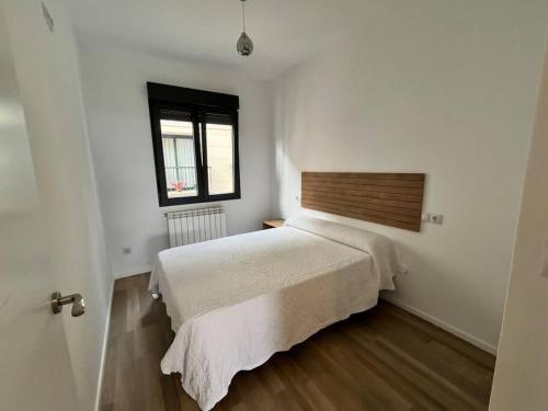 a bedroom with a white bed and a window at Piso 1 Línea 30M de Playa ALOJAMIENTOS VACAY in Bueu