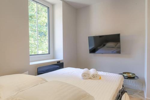 a white bedroom with a bed with towels on it at Superbe appartement, deux chambres, St-Didier in Saint-Didier-au-Mont-dʼOr