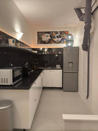 une cuisine avec des armoires blanches et un réfrigérateur en acier inoxydable dans l'établissement Marais, Sainte-croix Bretonnerie 2 - 4 places, à Paris