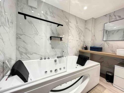 La salle de bains est pourvue d'une baignoire blanche et de murs en marbre. dans l'établissement BRP Cannes Center, Sixteen-Bedroom Luxury House, à Cannes