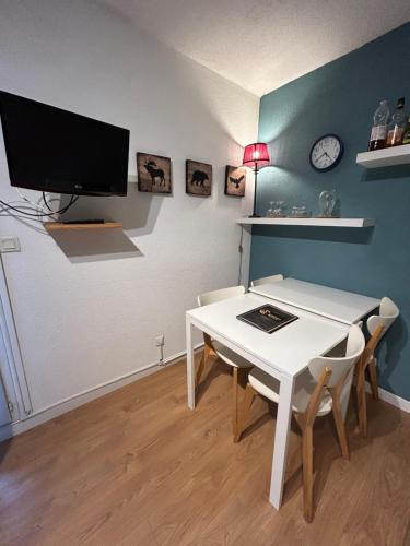 d'une salle à manger avec une table blanche et une télévision murale. dans l'établissement Havre de paix Climatisé parking T1, à Lourdes