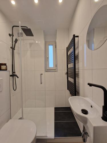 a white bathroom with a shower and a sink at Ferienwohnung in Krefeld in Krefeld
