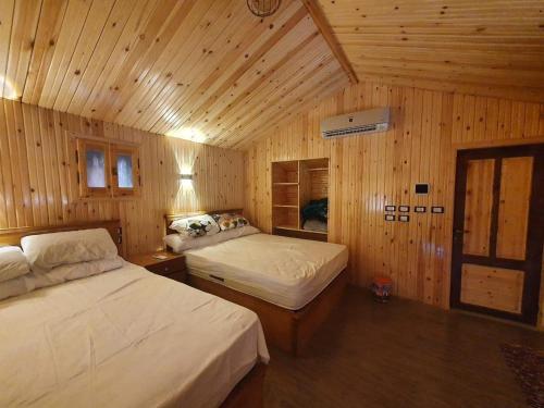 a bedroom with two beds in a wooden cabin at King swer in Taba