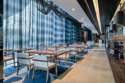 a dining room with tables and chairs and a wall of windows at Hilton Mexico City Santa Fe in Mexico City