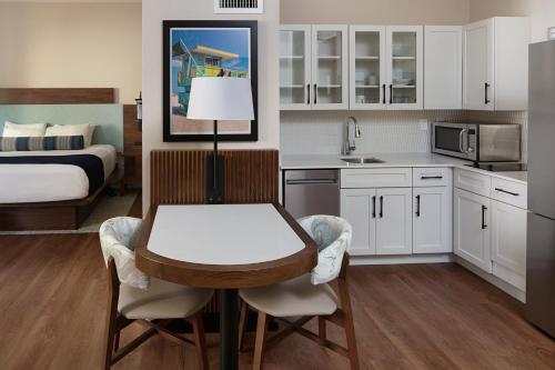a kitchen with a table and a bedroom with a bed at The Atlantic Suites on the Ave in Delray Beach