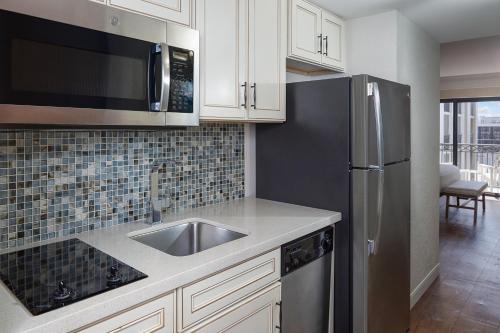 a kitchen with a sink and a stainless steel refrigerator at The Atlantic Suites on the Ave in Delray Beach