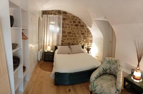 een slaapkamer met een bed en een stoel bij "La Voûte de Pierre" Gîte indépendant in Saint-Cyr