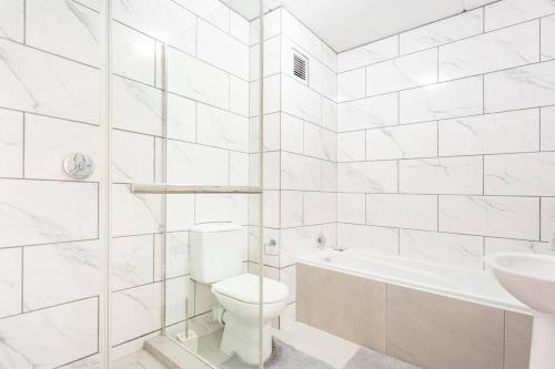 a white bathroom with a toilet and a sink at The Cozy Retreat, 2-bedroom Apartment in Parklands, Cape Town in Cape Town