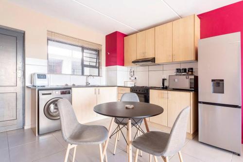 a kitchen with a table and chairs in a room at The Cozy Retreat, 2-bedroom Apartment in Parklands, Cape Town in Cape Town